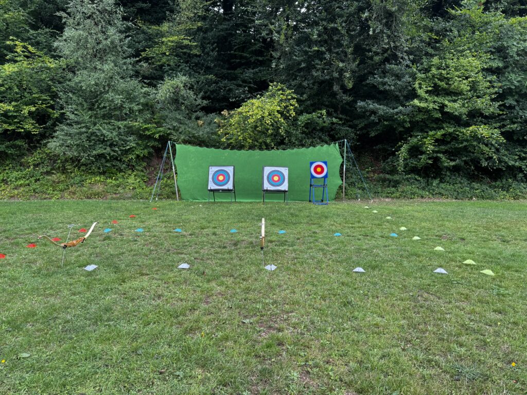 Archery range set out in front of trees with a net, targets and cones laid out on the ground.